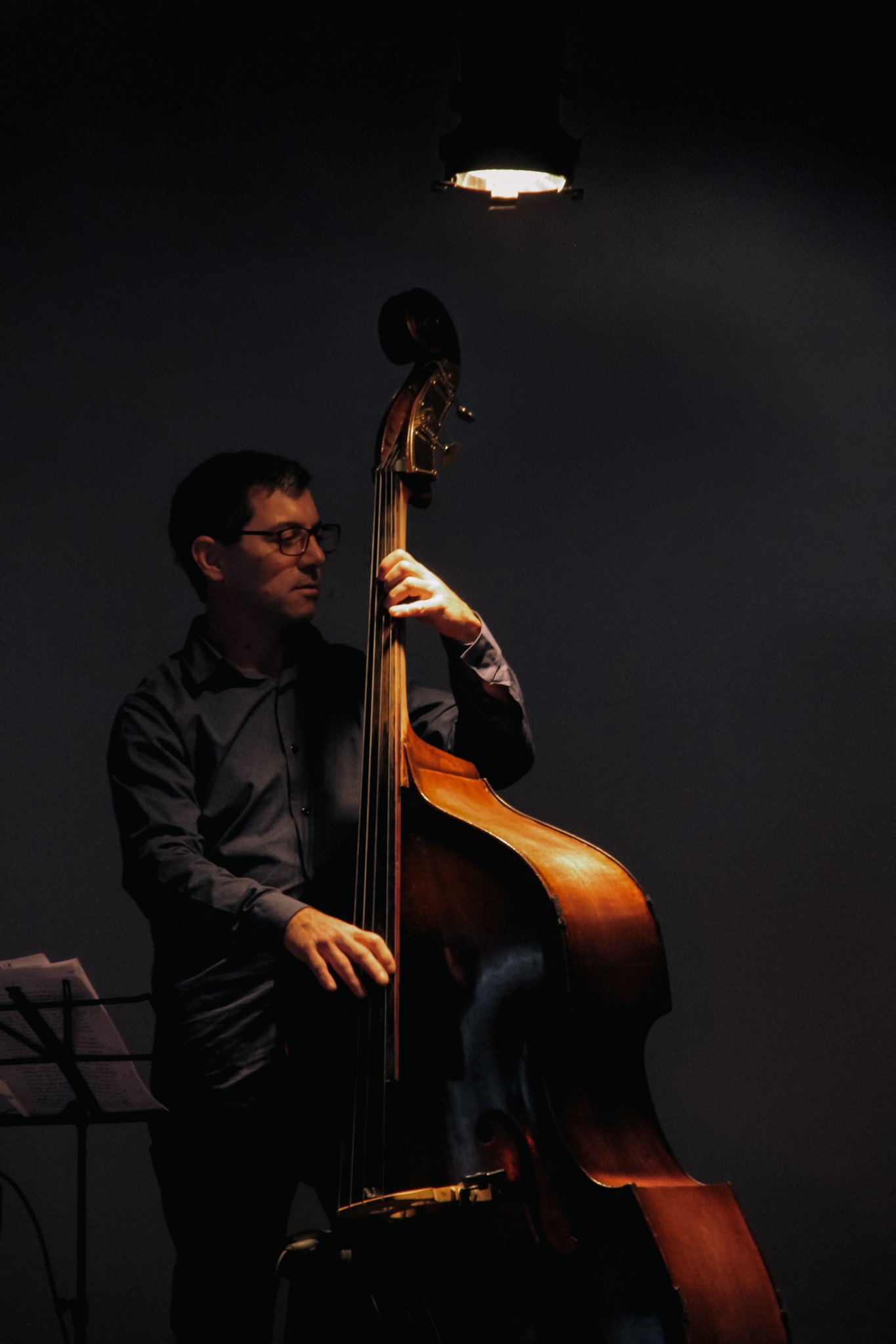 Músico tocando el contrabajo bajo una luz cenital